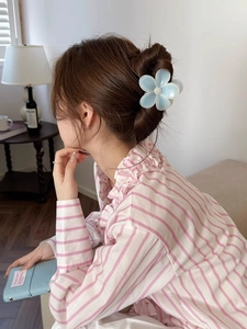 Détail d'une pince à cheveux en résine bleue claire portée sur un chignon élégant
