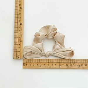Chouchou à nœud en satin champagne de 14 cm de large, présenté sur un fond blanc épuré