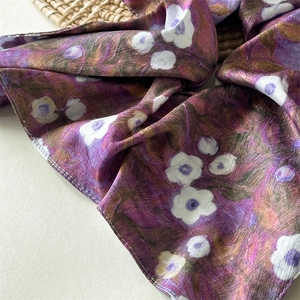 Close-up detail of smooth satin fabric with purple floral ink patterns for hair accessory