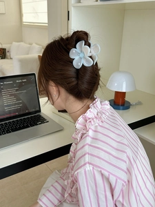 Gros plan d'une pince à cheveux fleur bleue claire portée dans un bureau moderne