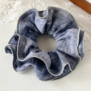 Close-up of blue striped scrunchie with silver threads and elegant metallic edge detailing
