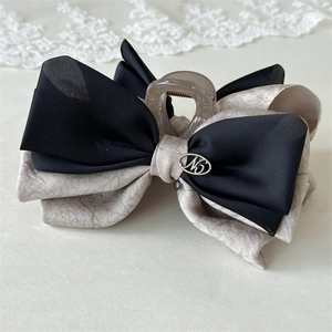 Close-up of elegant bow hair claw clip with black chiffon and N5 metal emblem detail