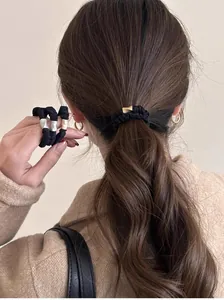 Détail du chouchou noir élastique avec décoration métallique et perle sur cheveux