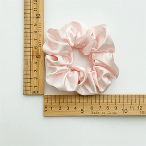 Pink silk satin scrunchie shown with a ruler measuring a 10cm diameter size