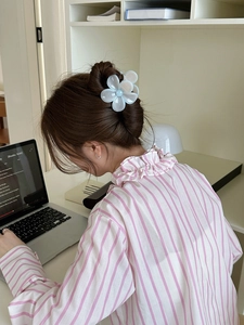 Pince à cheveux fleur bleu clair sur une coiffure élégante demi-attachée pour femme