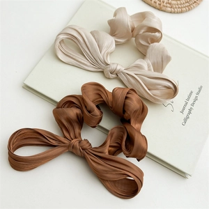 Détail de chouchous à nœud en satin plissé de couleurs or champagne et marron foncé