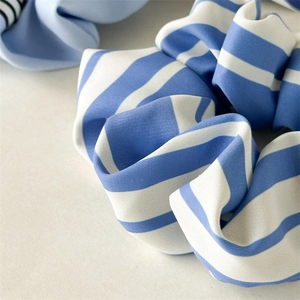 Détails d'un chouchou en satin à rayures bleues et blanches montrant les plis du tissu