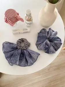 Detail of blue-grey chiffon scrunchies with silver silk stripes on a white table