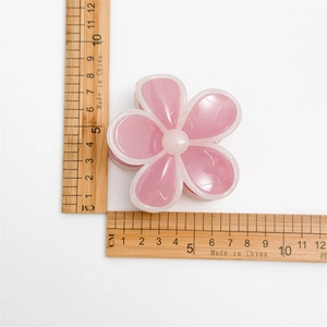 Gros plan d'une pince à cheveux fleur rose avec mesure de taille sur fond blanc