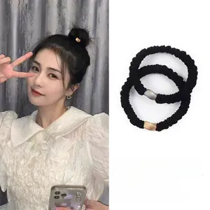 Détail de chouchous noirs avec boucles métalliques et mannequin portant l'élastique durable