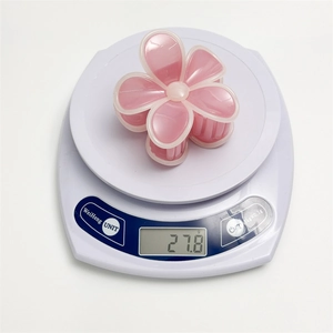 Vue détaillée d'une pince à cheveux fleur rose de 27,8g sur une balance