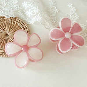 Détail des pinces à cheveux florales en résine lisse sur un fond de dentelle blanche