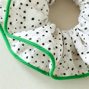 Détails d'un chouchou blanc à pois avec une bordure tressée verte de haute qualité
