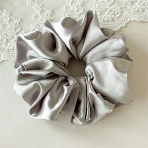 Détail d'un grand chouchou en satin gris argenté sur fond élégant en dentelle blanche