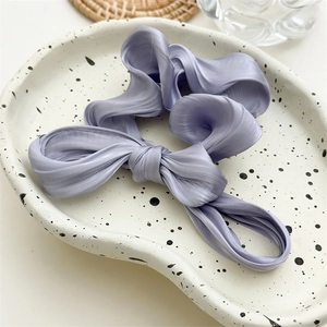 Gros plan d'un chouchou à nœud violet lavande sur une assiette décorative en céramique
