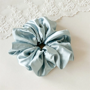 Vue détaillée du grand chouchou en satin bleu glacé avec plis doux et texture soyeuse