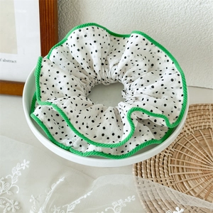 Gros plan d'un chouchou à pois avec bordure verte dans un bol en céramique