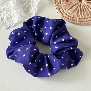 Vue détaillée d'un chouchou violet à motifs d'étoiles sur un fond plat élégant