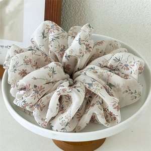 Macro detail of large floral chiffon scrunchie with vintage daisy pattern on a tray