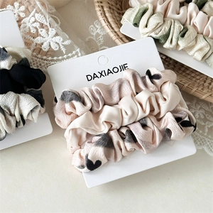 Dettaglio di tre elastici scrunchies con motivi a cuore su cartoncino bianco liscio