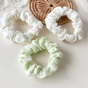 Detailed shot of three-piece scrunchie set with green polka dots and satin finish textures