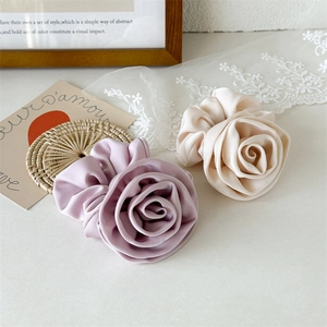 Close-up of elegant satin rose scrunchies in cream and lilac with a handmade texture