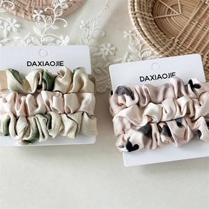Dettaglio di set da tre elastici per capelli in raso con eleganti motivi floreali