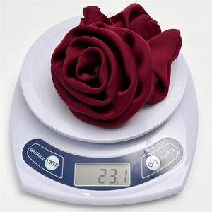 Macro detail of wine red satin flower hair tie on electronic scale weighing 23.1 grams