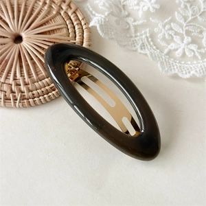 Detail van elegante amberkleurige hars haarclip met gouden metalen clip op kant achtergrond