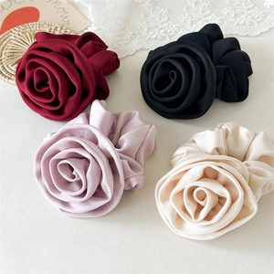 Detailed view of four satin rose scrunchies in wine red, black, purple and beige colors