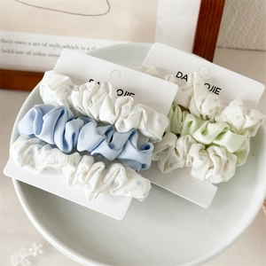 Detailed set of ruffled hair scrunchies in solid colors and polka dots on a display card