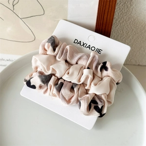 Dettaglio di elastici scrunchies in raso rosa con cuori su carta per capelli eleganti