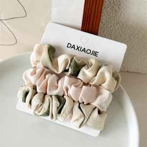Dettaglio di un set di elastici scrunchies in raso rosa e beige su carta display