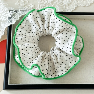 Détail d'un chouchou géant à pois blancs avec bordure verte contrastante sur plateau