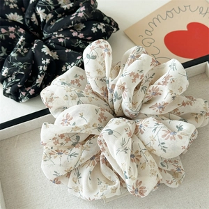 Detail of floral chiffon scrunchies with soft ruffles in a decorative beige tray