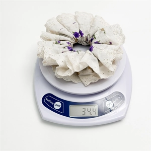 Detail shot showing a floral scrunchie with lace trim weighing 34.4g on a digital scale