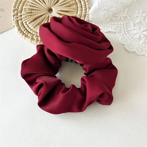 Detailed view of dark red satin rose hair scrunchie with elegant petal textures