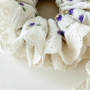Detailed close-up of floral scrunchie with lace trim and fine embroidery texture