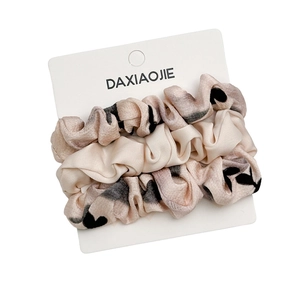 Set di tre elastici per capelli in raso beige con cuori neri su scheda di presentazione