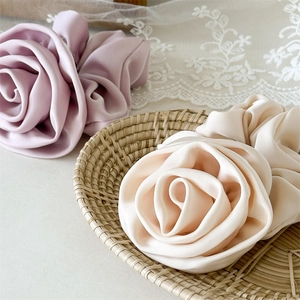 Detailed view of handmade satin rose hair scrunchies in soft lilac and elegant beige tones