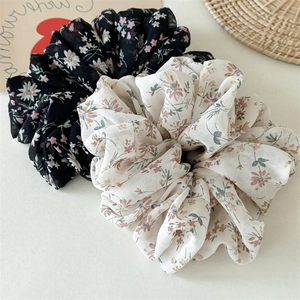 Close-up of floral chiffon hair scrunchies in black and cream with soft aesthetic detail