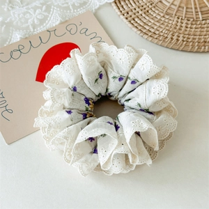 Detailed macro view of floral scrunchie with delicate white embroidery lace edging
