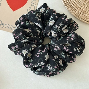 Detail of a black floral chiffon scrunchie with pink flowers and pleated texture