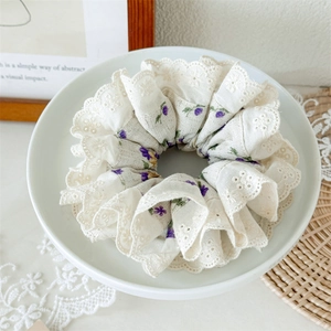 Detailed macro view of the floral lace scrunchie with intricate white hollow edges