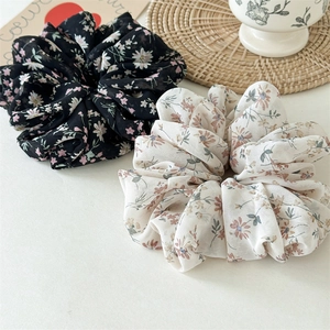 Detail of floral chiffon scrunchies in black and beige displayed with rustic props