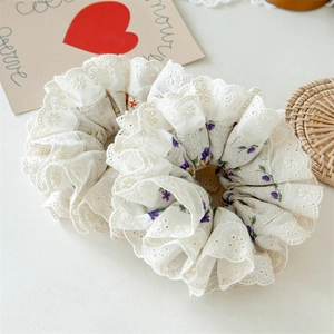 Close-up of floral scrunchie featuring delicate white lace trim and cotton texture