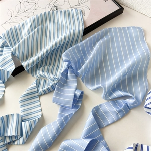 Detailed view of striped blue silk scarf with soft satin texture for hair styling