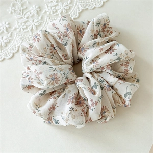Detailed macro view of the floral chiffon scrunchie with red flowers and green leaves