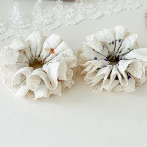 Close-up of floral hair scrunchies with white hollow lace edges and fine stitching