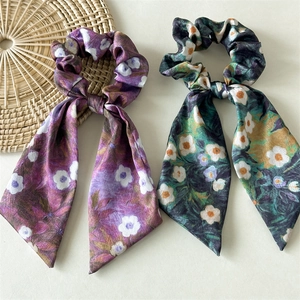 Detail of floral satin scrunchies with ribbons in purple and dark green daisy patterns
